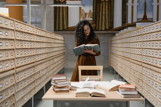 A woman reads a book in a card catalog room, surrounded by archival records.
