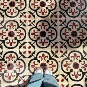 Stylish photo of patterned tiles with feet in jeans and sneakers.