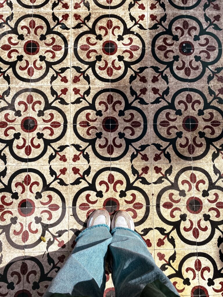 Stylish photo of patterned tiles with feet in jeans and sneakers.